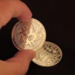 Fingers Holding Silver Round Coin