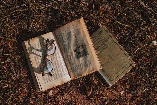 Old books with eyeglasses on dry grass