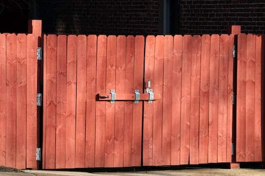 The red fence made of wood has the gate locked.
